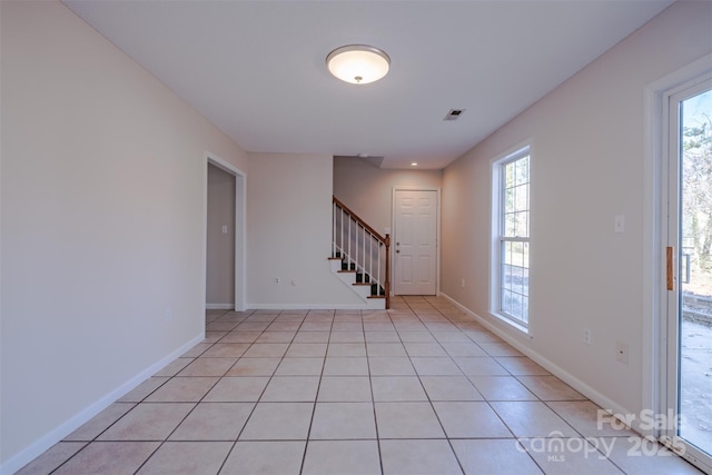 foyer featuring light tile patterned flooring, stairway, visible vents, and a wealth of natural light