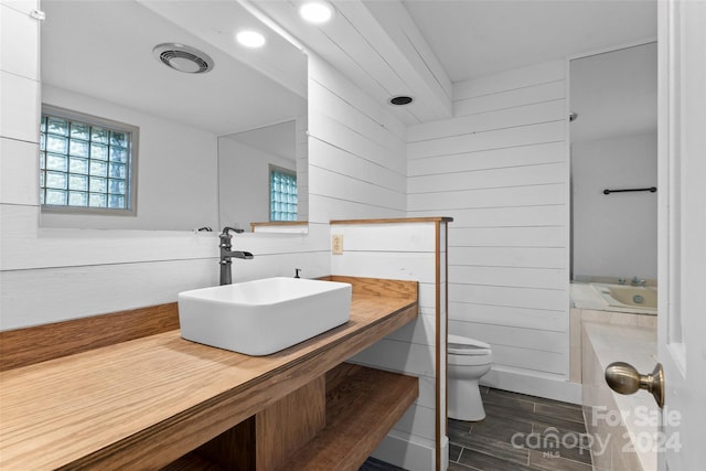 bathroom with toilet, hardwood / wood-style floors, wooden walls, and sink