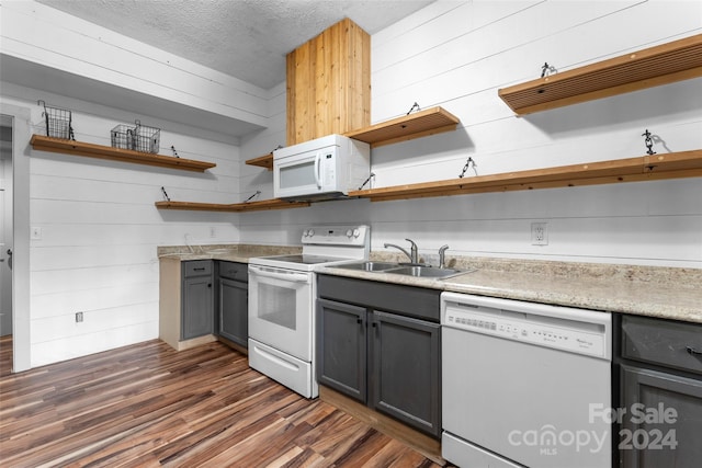 kitchen with wood walls, sink, dark hardwood / wood-style floors, white appliances, and gray cabinetry