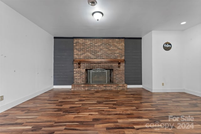 unfurnished living room with a brick fireplace and dark hardwood / wood-style floors