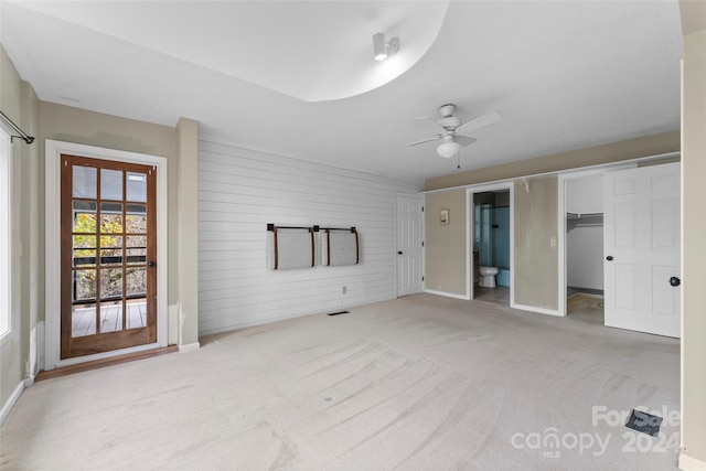 unfurnished bedroom featuring access to outside, ensuite bath, light carpet, ceiling fan, and a closet