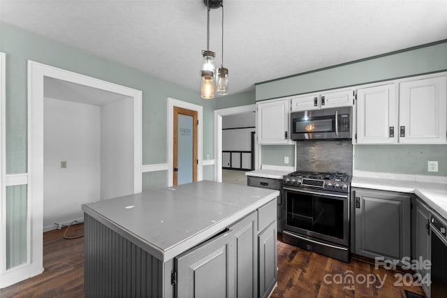 kitchen featuring white cabinets, stainless steel appliances, decorative light fixtures, and a kitchen island