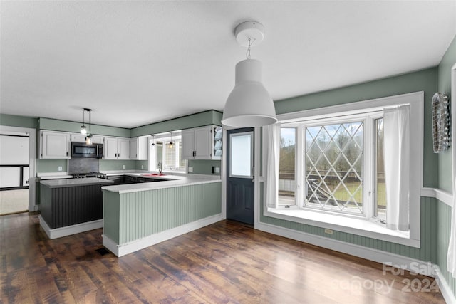 kitchen featuring appliances with stainless steel finishes, dark hardwood / wood-style floors, decorative light fixtures, a center island, and white cabinets