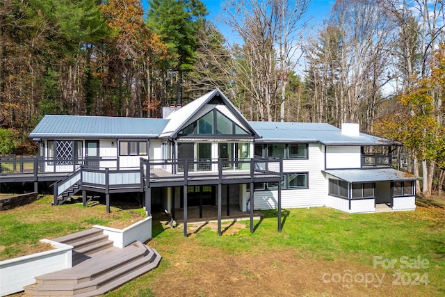 rear view of house featuring a deck, a sunroom, and a yard