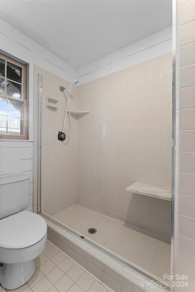 bathroom featuring toilet, tiled shower, and tile patterned floors