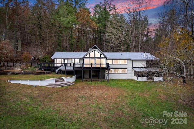 back house at dusk featuring a yard and a deck