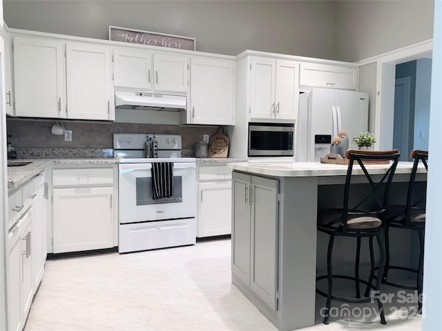 kitchen with white cabinets, white appliances, decorative backsplash, and a center island