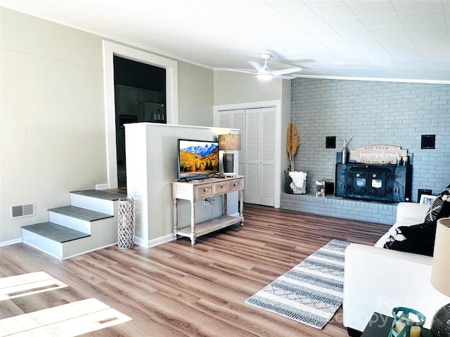 living room featuring wood-type flooring, ornamental molding, lofted ceiling, ceiling fan, and brick wall