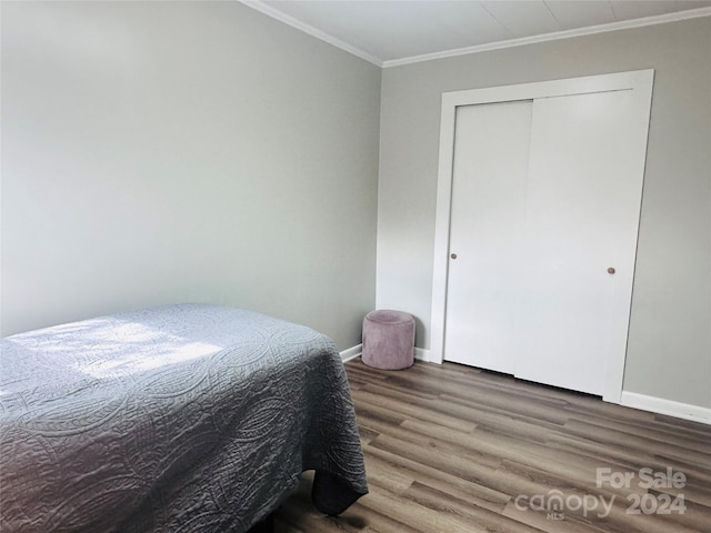 bedroom featuring wood-type flooring, a closet, and crown molding