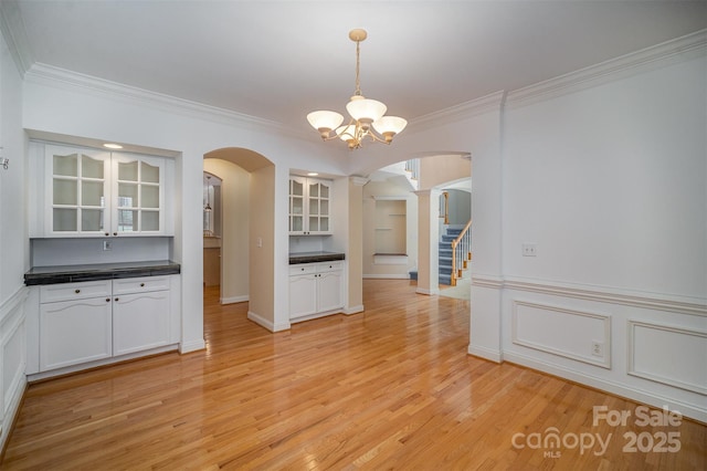 unfurnished dining area featuring light hardwood / wood-style floors, ornamental molding, and a chandelier