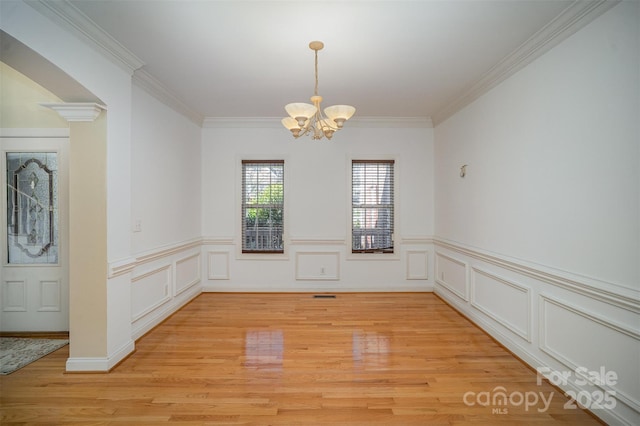 unfurnished dining area with crown molding, light hardwood / wood-style floors, and a notable chandelier