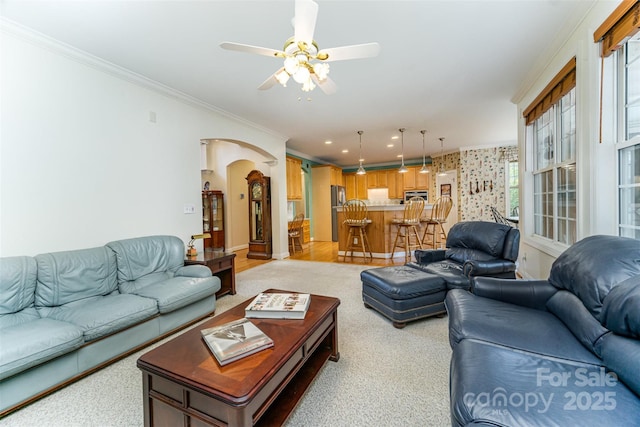 living room with ceiling fan, a wealth of natural light, and ornamental molding