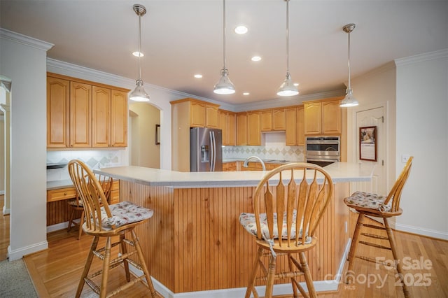 kitchen with appliances with stainless steel finishes, decorative backsplash, ornamental molding, and a breakfast bar