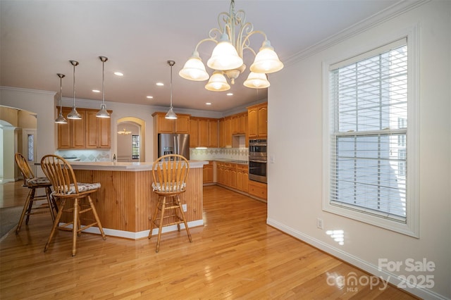 kitchen featuring stainless steel appliances, crown molding, tasteful backsplash, and a breakfast bar