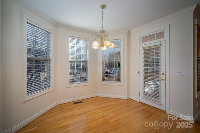 unfurnished dining area with wood-type flooring, an inviting chandelier, and ornamental molding