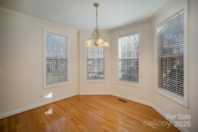 unfurnished dining area with hardwood / wood-style flooring, ornamental molding, and a notable chandelier