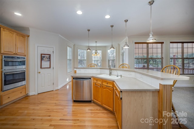 kitchen featuring an island with sink, stainless steel appliances, hanging light fixtures, light hardwood / wood-style flooring, and sink