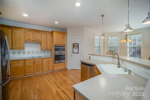 kitchen featuring pendant lighting, appliances with stainless steel finishes, tasteful backsplash, sink, and light hardwood / wood-style flooring