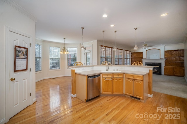 kitchen with light hardwood / wood-style floors, stainless steel dishwasher, a center island with sink, sink, and hanging light fixtures