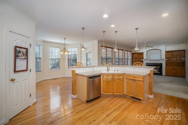 kitchen featuring dishwasher, an island with sink, light hardwood / wood-style floors, sink, and hanging light fixtures