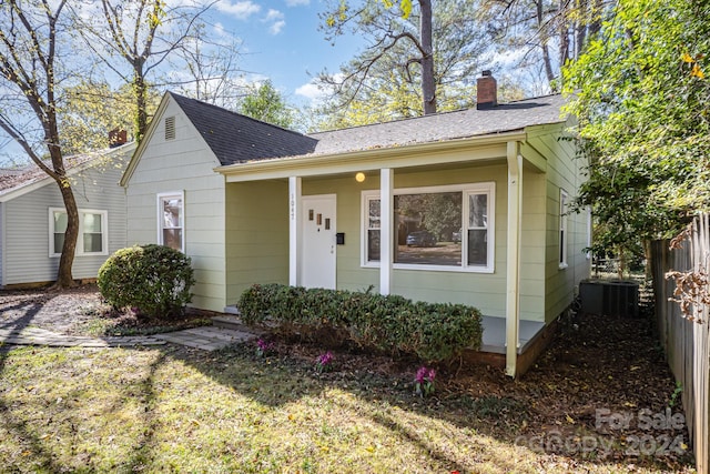 view of front facade with central air condition unit, a porch, and a front yard