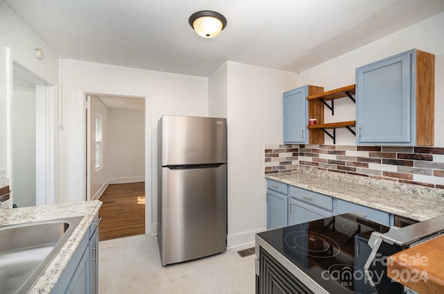 kitchen with stainless steel refrigerator, sink, backsplash, light hardwood / wood-style flooring, and blue cabinets