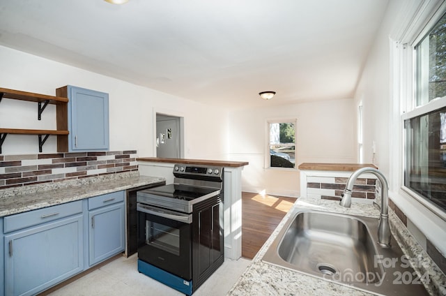 kitchen featuring black electric range, blue cabinets, sink, backsplash, and light wood-type flooring