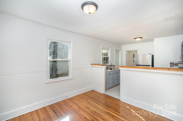 interior space with light hardwood / wood-style flooring, sink, and stainless steel fridge