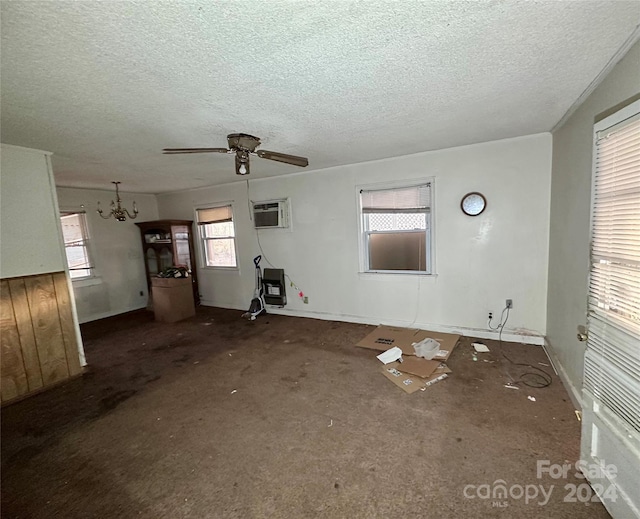 unfurnished living room featuring a textured ceiling, ceiling fan with notable chandelier, dark carpet, and a wall unit AC