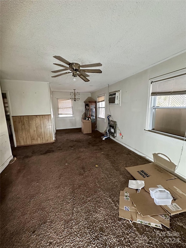 unfurnished living room with dark colored carpet, a textured ceiling, and a wealth of natural light