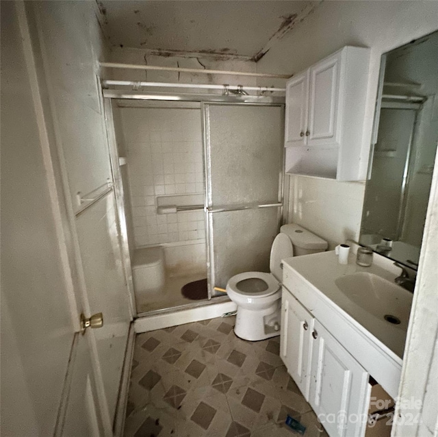 bathroom featuring vanity, toilet, and a shower with shower door