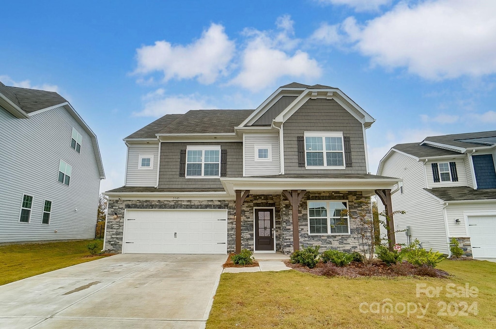 craftsman-style home featuring covered porch, a garage, and a front yard