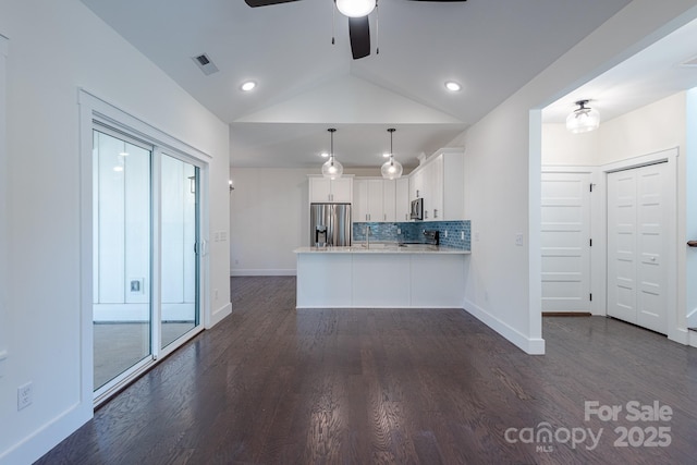 kitchen with lofted ceiling, kitchen peninsula, hanging light fixtures, stainless steel appliances, and white cabinets