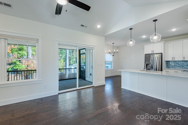 kitchen featuring lofted ceiling, decorative light fixtures, tasteful backsplash, stainless steel refrigerator with ice dispenser, and white cabinets