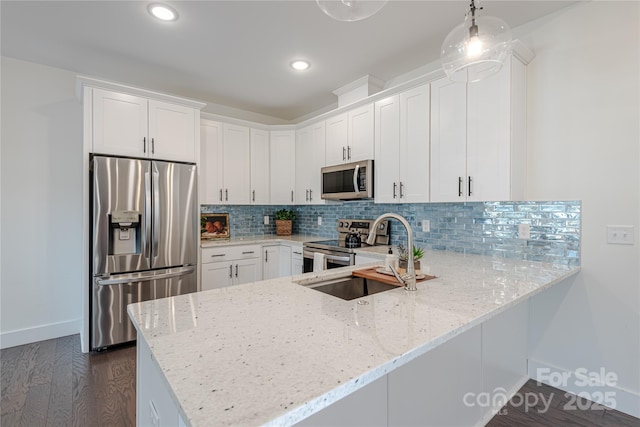 kitchen with appliances with stainless steel finishes, pendant lighting, white cabinets, and sink