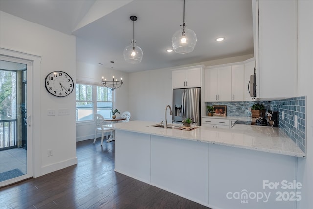 kitchen with hanging light fixtures, white cabinets, appliances with stainless steel finishes, and sink