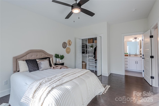 bedroom featuring ceiling fan, ensuite bath, sink, dark wood-type flooring, and a closet