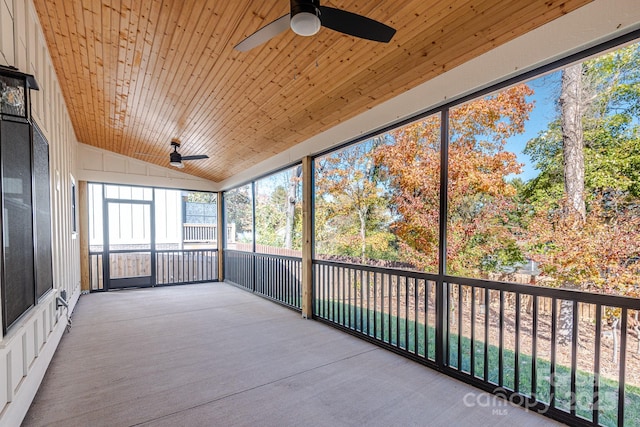 unfurnished sunroom featuring ceiling fan, wooden ceiling, a healthy amount of sunlight, and vaulted ceiling