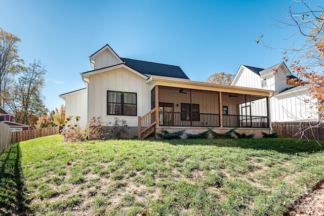 rear view of property featuring ceiling fan, a sunroom, and a yard