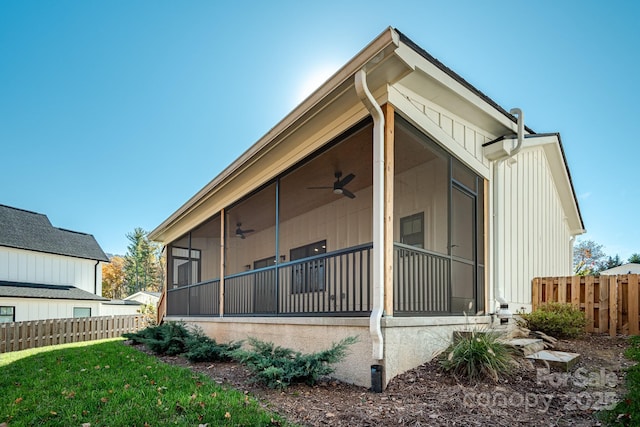 view of side of property featuring ceiling fan, a sunroom, and a lawn