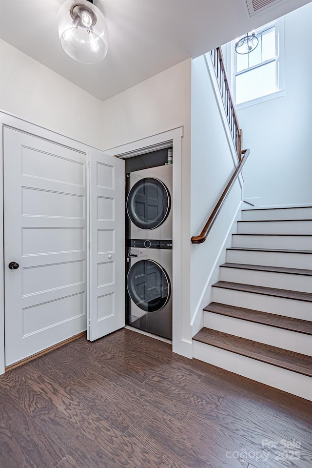 laundry room featuring dark wood-type flooring and stacked washing maching and dryer