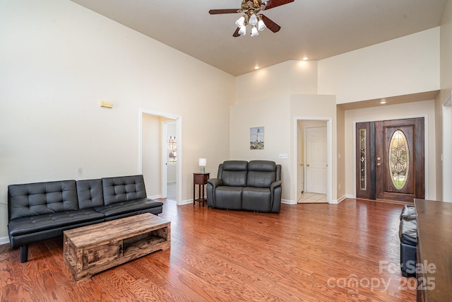 living room with ceiling fan, hardwood / wood-style floors, and a high ceiling