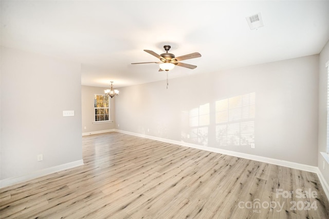 unfurnished room with ceiling fan with notable chandelier and light hardwood / wood-style floors