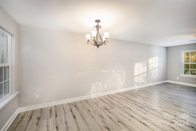 empty room with a chandelier and light wood-type flooring