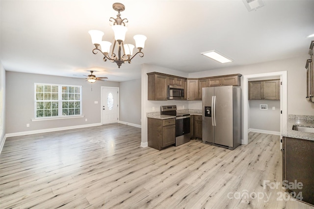 kitchen featuring light stone counters, light hardwood / wood-style floors, decorative light fixtures, ceiling fan with notable chandelier, and appliances with stainless steel finishes