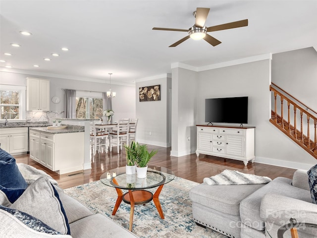 living room with ceiling fan with notable chandelier, dark hardwood / wood-style floors, plenty of natural light, and ornamental molding