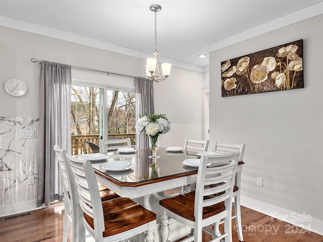 dining area featuring ornamental molding, dark wood-type flooring, and a notable chandelier