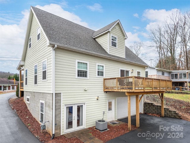 rear view of property with a wooden deck, french doors, cooling unit, and a garage