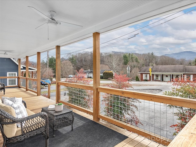 sunroom with ceiling fan and a mountain view