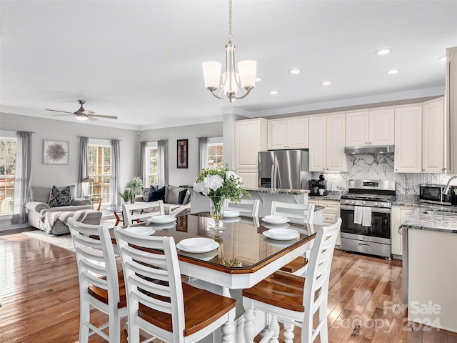 dining area featuring ceiling fan with notable chandelier, light hardwood / wood-style flooring, and sink